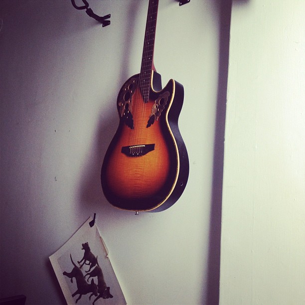 guitar hanging on wall next to book rack and po