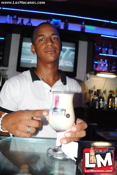 a man holding up an alcoholic drink in front of a bar