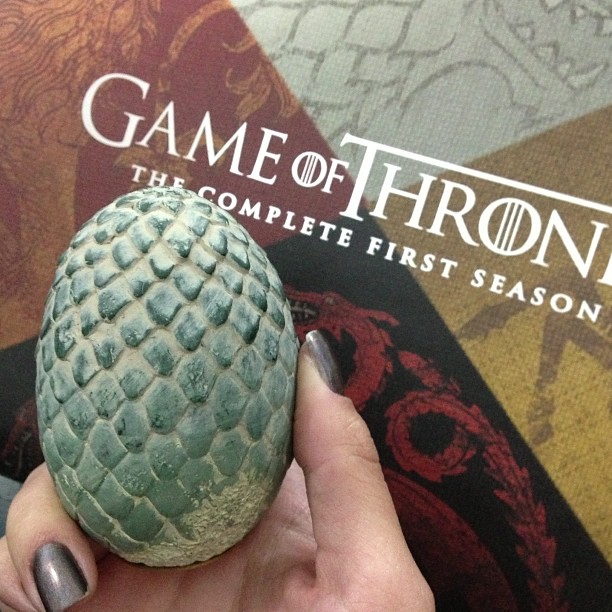 a hand is holding an object in front of the game of throne book