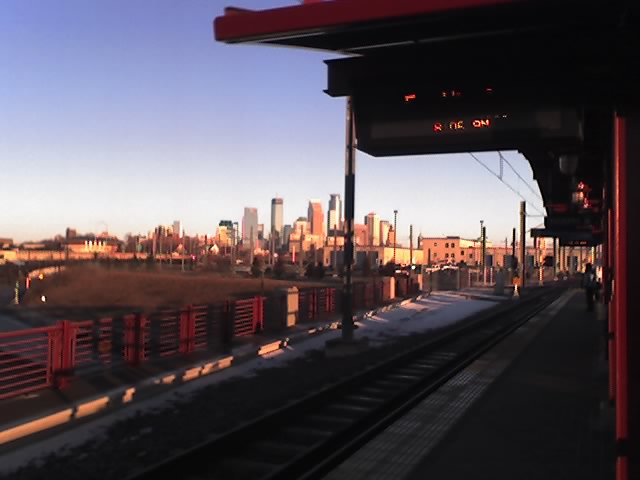 the skyline seen through a train window with a red train track going by