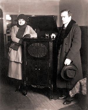 a man and woman in a room standing next to an old radio