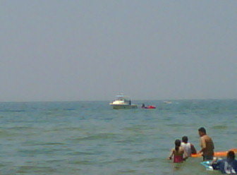 a group of people in the ocean with a boat in the background