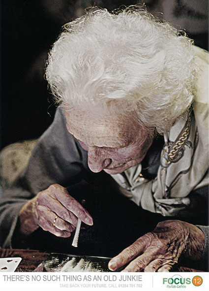 a woman reading and smoking a cigarette on top of a desk