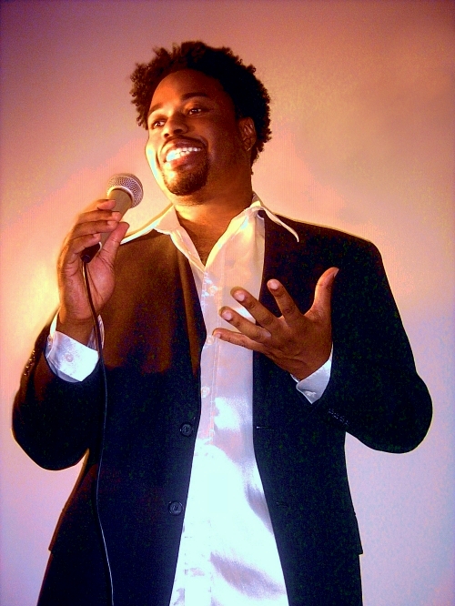 a man with curly hair standing up to a microphone