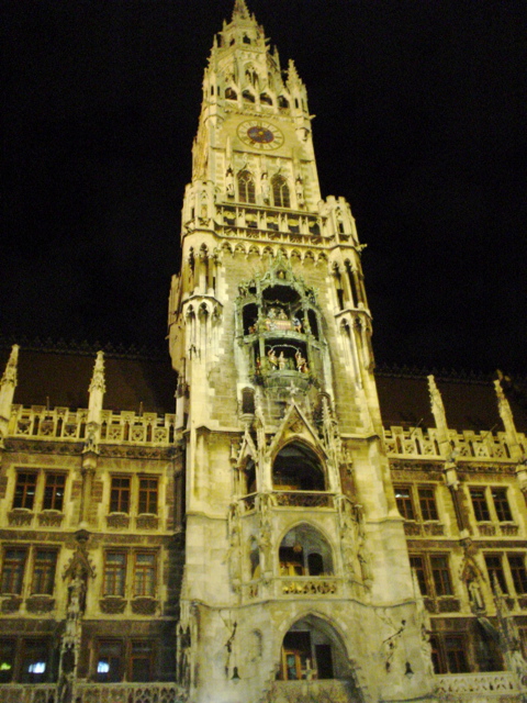 an illuminated large building with a tower next to it