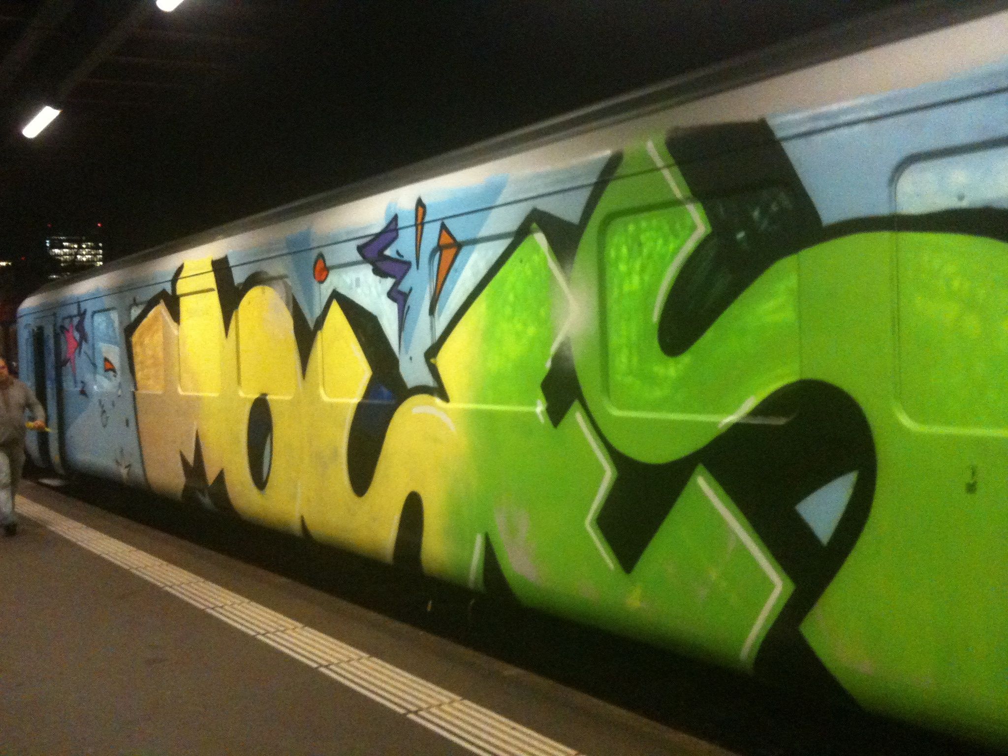 a person is standing near a colorful graffiti covered train