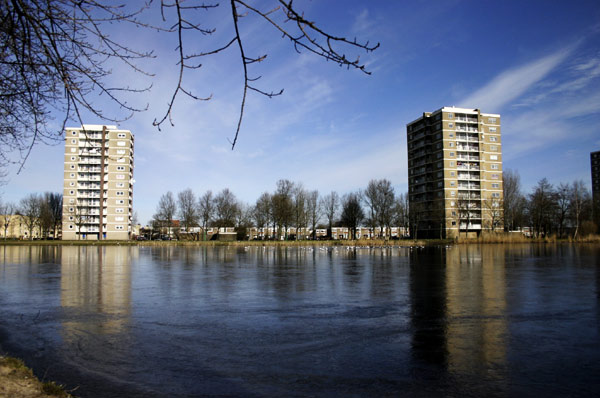 two apartment buildings on the shore of a body of water