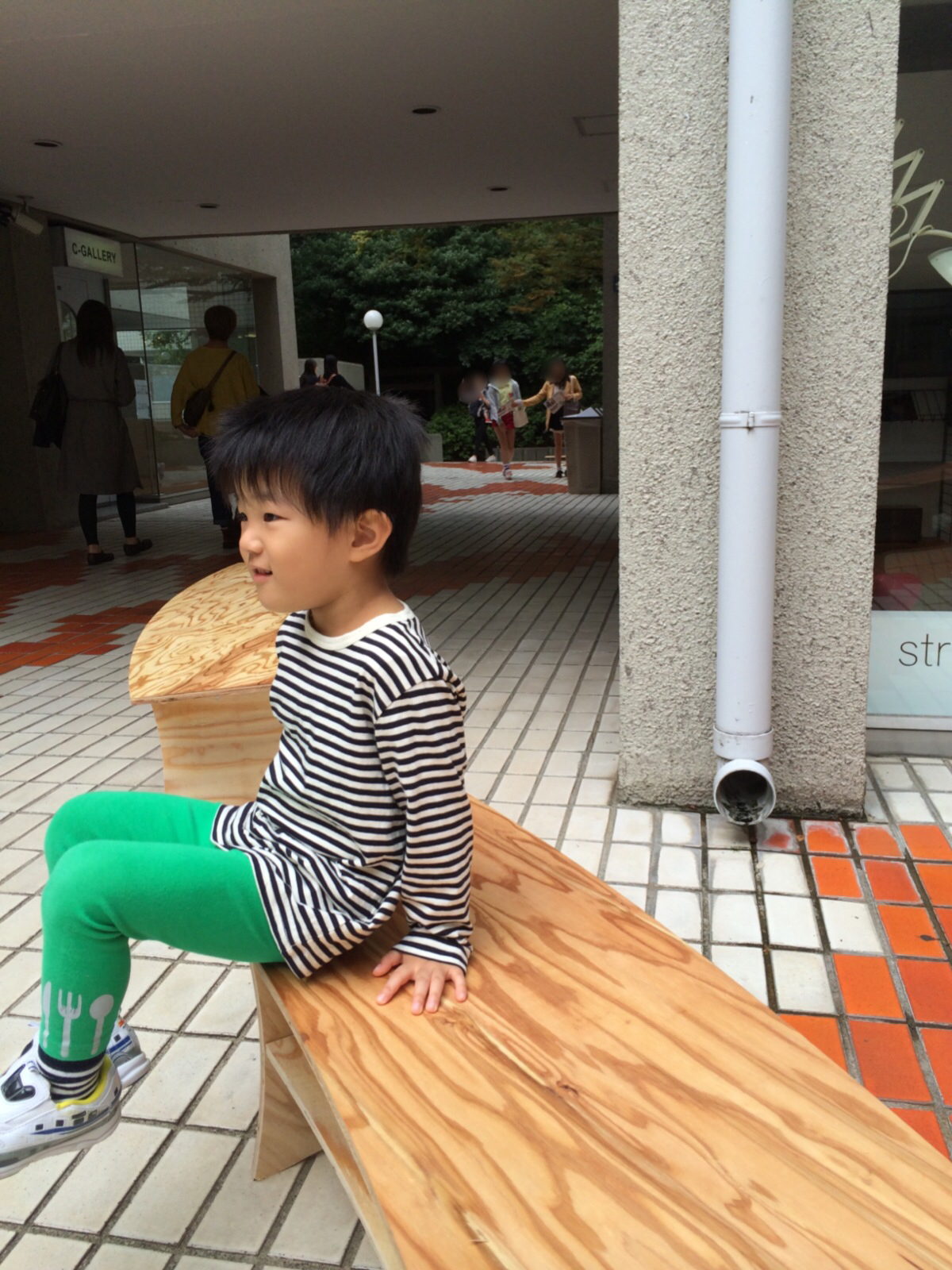 little girl wearing a long sleeve shirt sitting on a bench