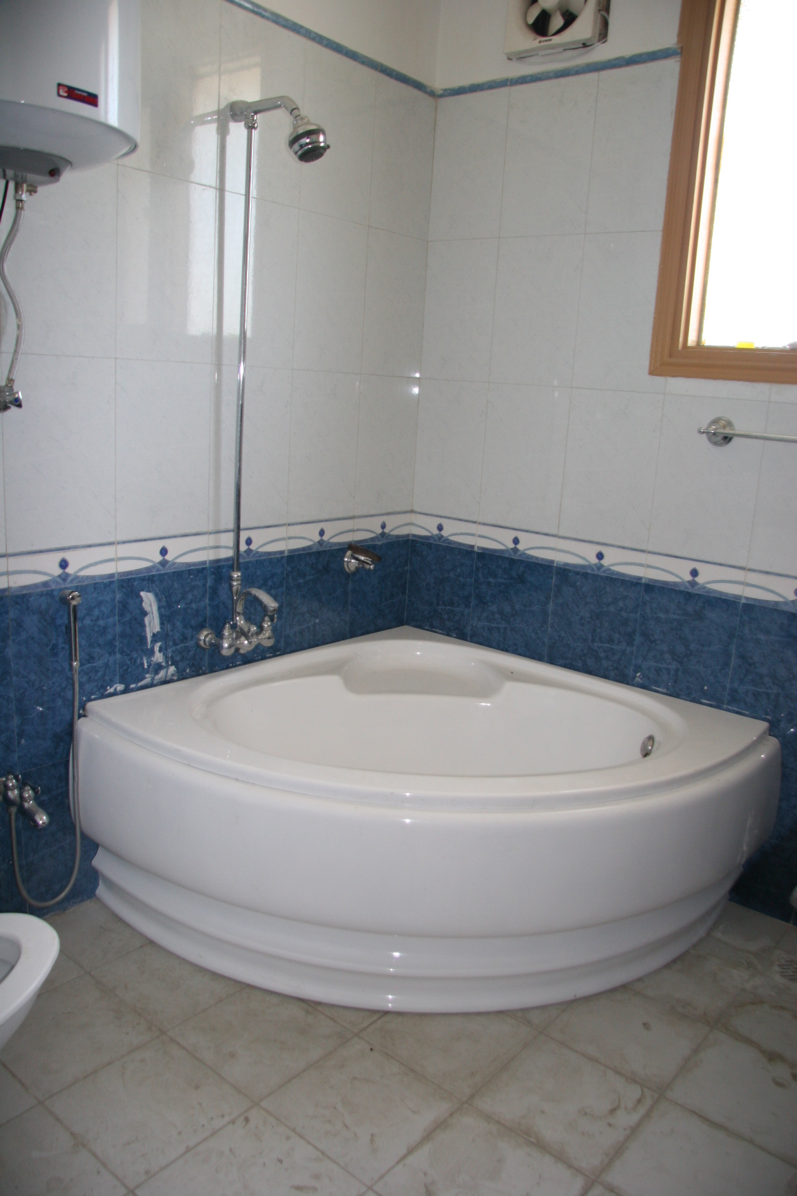 a bathtub in a bathroom with blue tile and a round window