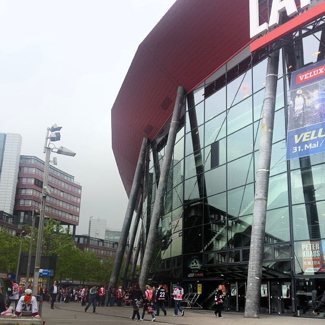 the exterior of a stadium with a lot of people walking by