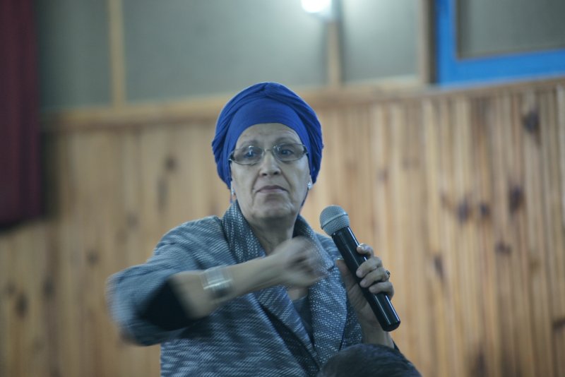 woman wearing blue head covering holding up a microphone