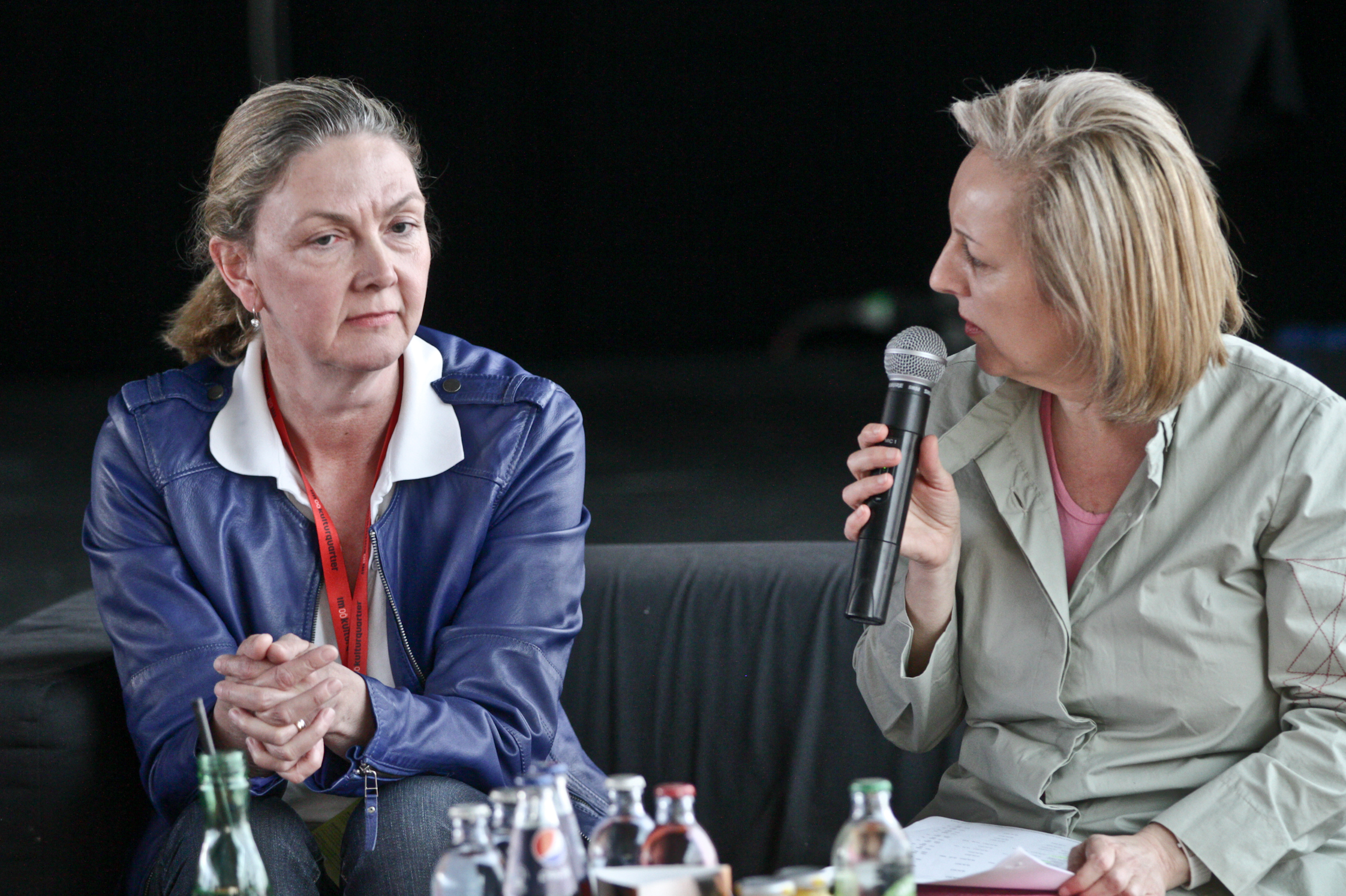 two women sitting at a table holding microphones