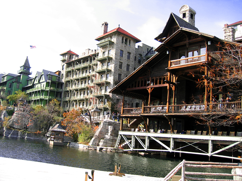 an old wooden house sitting next to water in front of some buildings