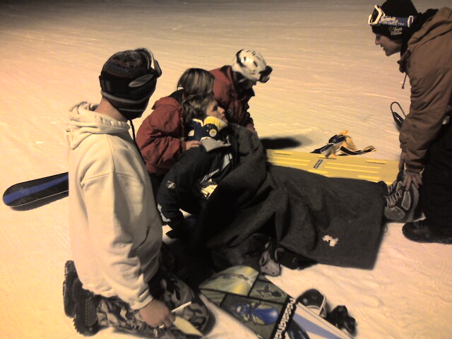 a group of snowboarders are gathered around some gear
