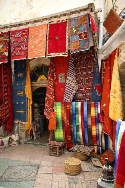 a multicolored street scene with many fabrics on display