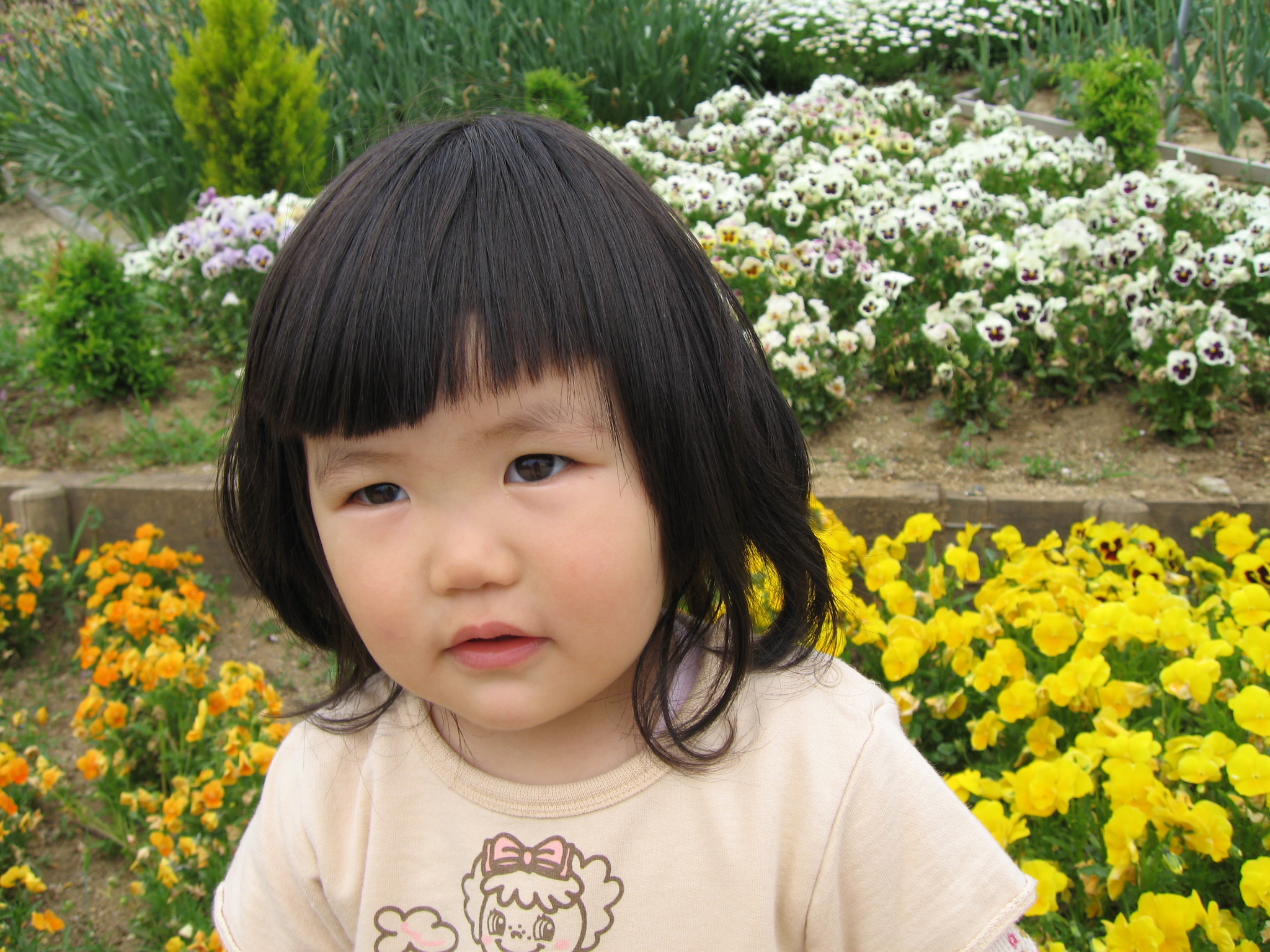 a little girl standing next to a field full of flowers