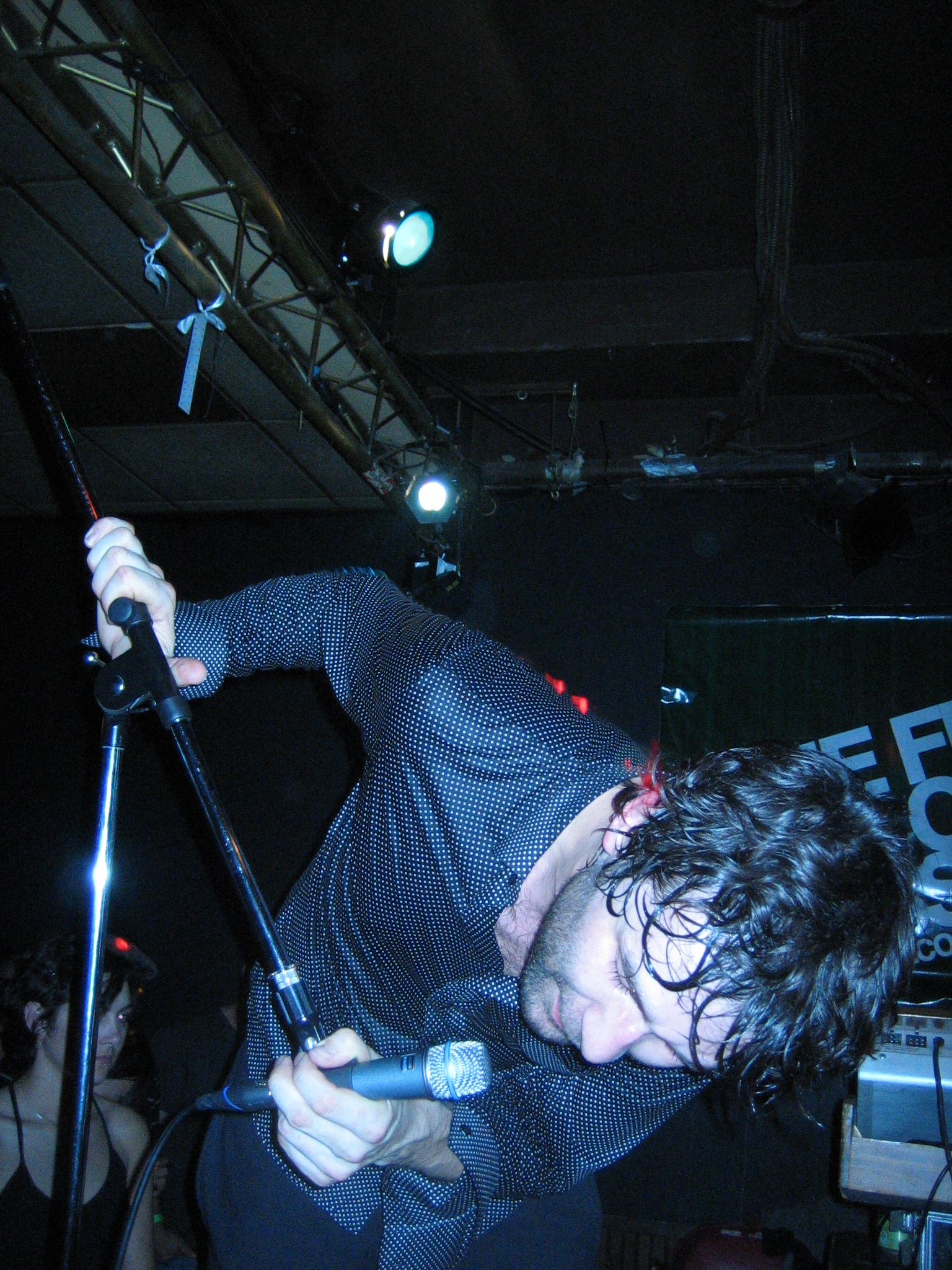 a young man with curly hair playing on a metal pole
