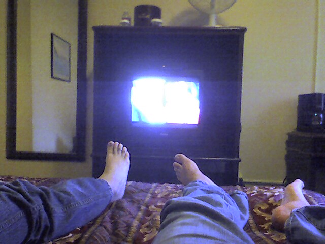 a person's legs with their feet up in front of a television