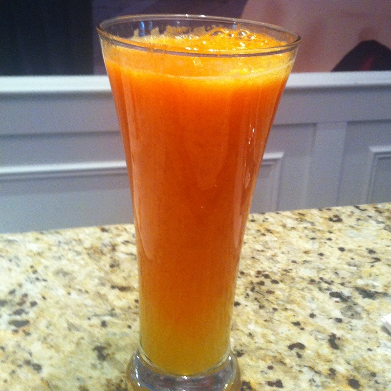 orange juice in a tall glass on top of a table