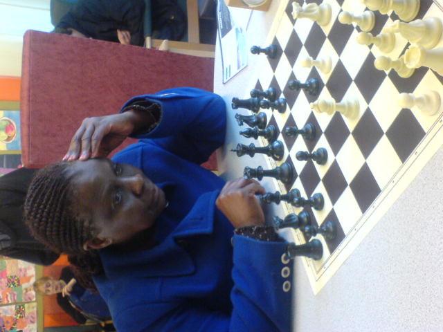 a young man playing chess while someone watches