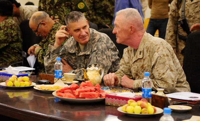 men in military uniforms are seated around a table