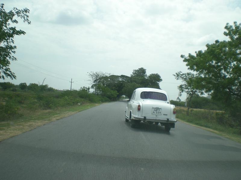 an old car driving on the road down a country side