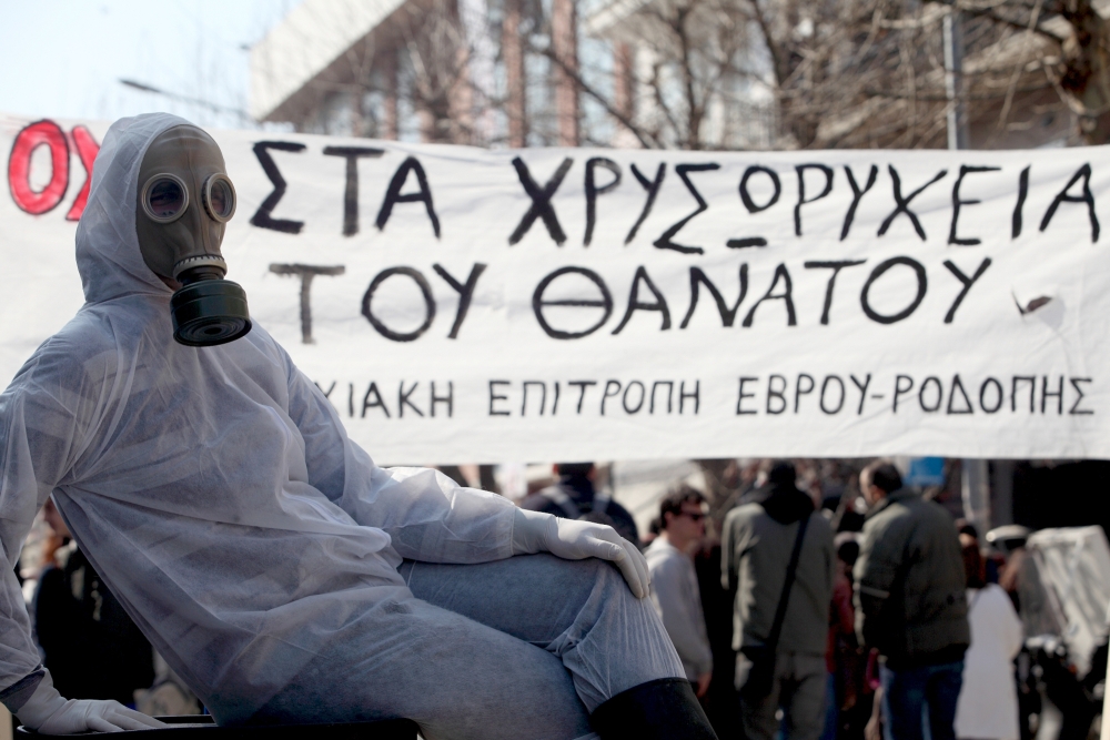 protestors in gas masks in the background with a banner