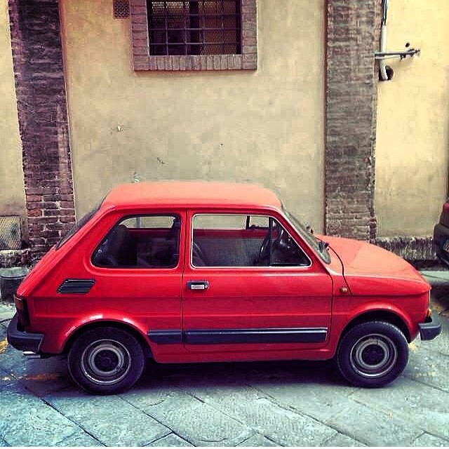 a red hatchback hatchback sitting on the side of a building