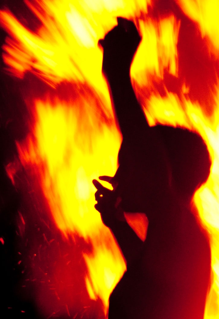 a person standing next to a large bush on fire