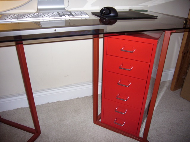 the office desk has a red drawer on top