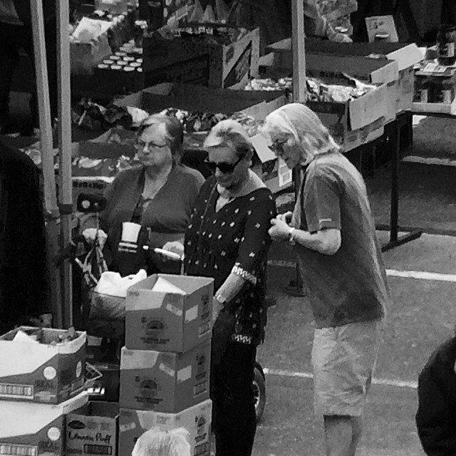 three elderly women looking at a small carton