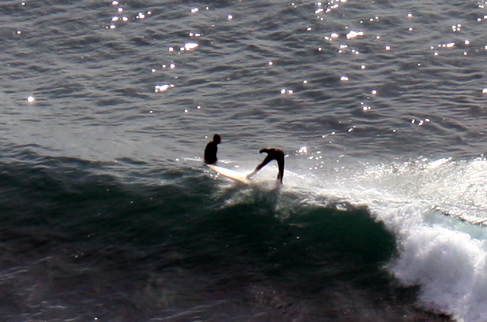 two surfers in black wet suits riding the waves
