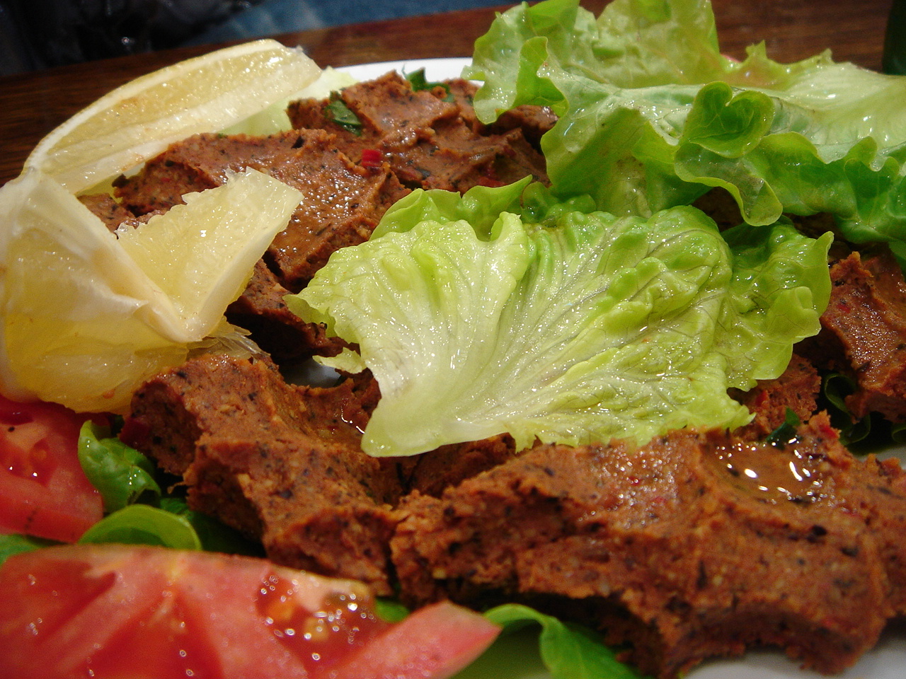 some lettuce, lemon and tomato salad on a white plate