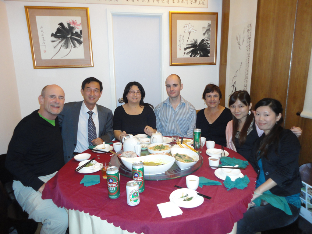 four people are sitting around a red round table with food on it