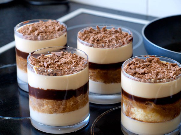 four desserts on a glass table that look like glasses with desserts in them