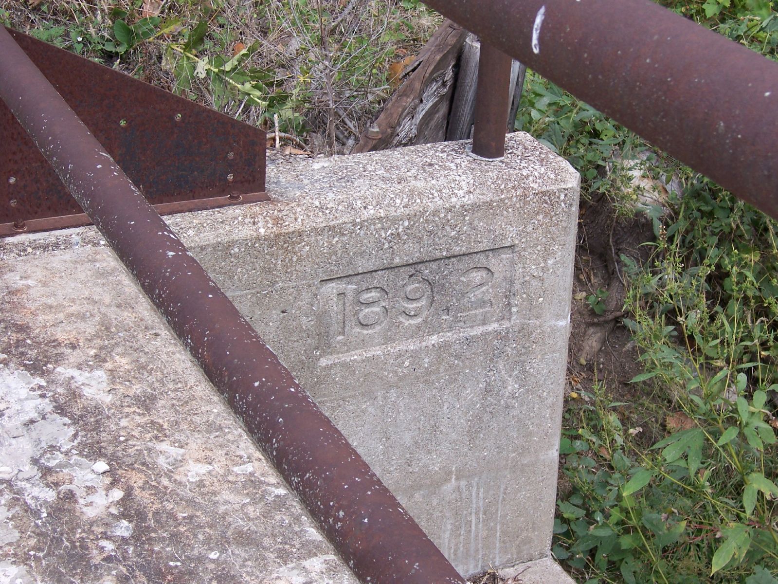 a very old concrete base near some rusty pipe