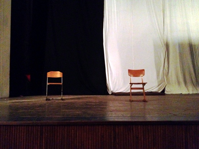 a theater stage with an empty chair and curtain