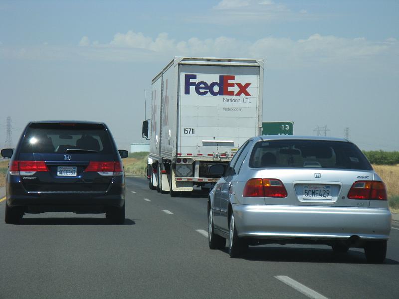 a silver car, white truck and grey car on street