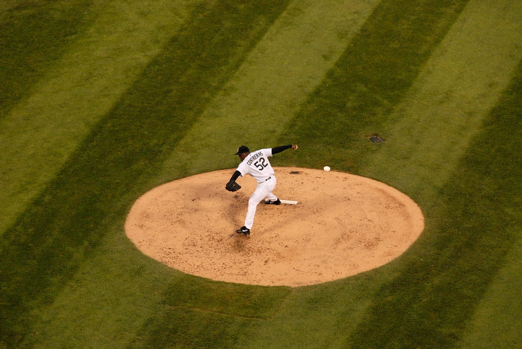 a man is throwing a baseball from the pitcher's mound