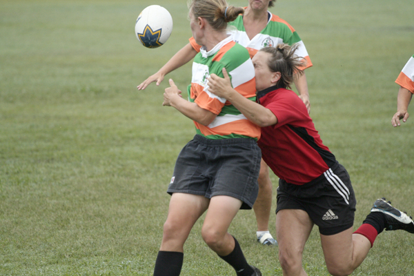 a woman grabbing her arm while trying to block a soccer ball