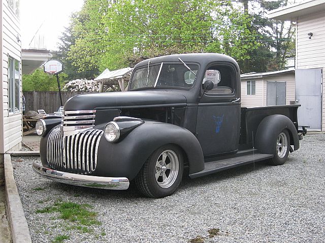 an old style black truck in the driveway