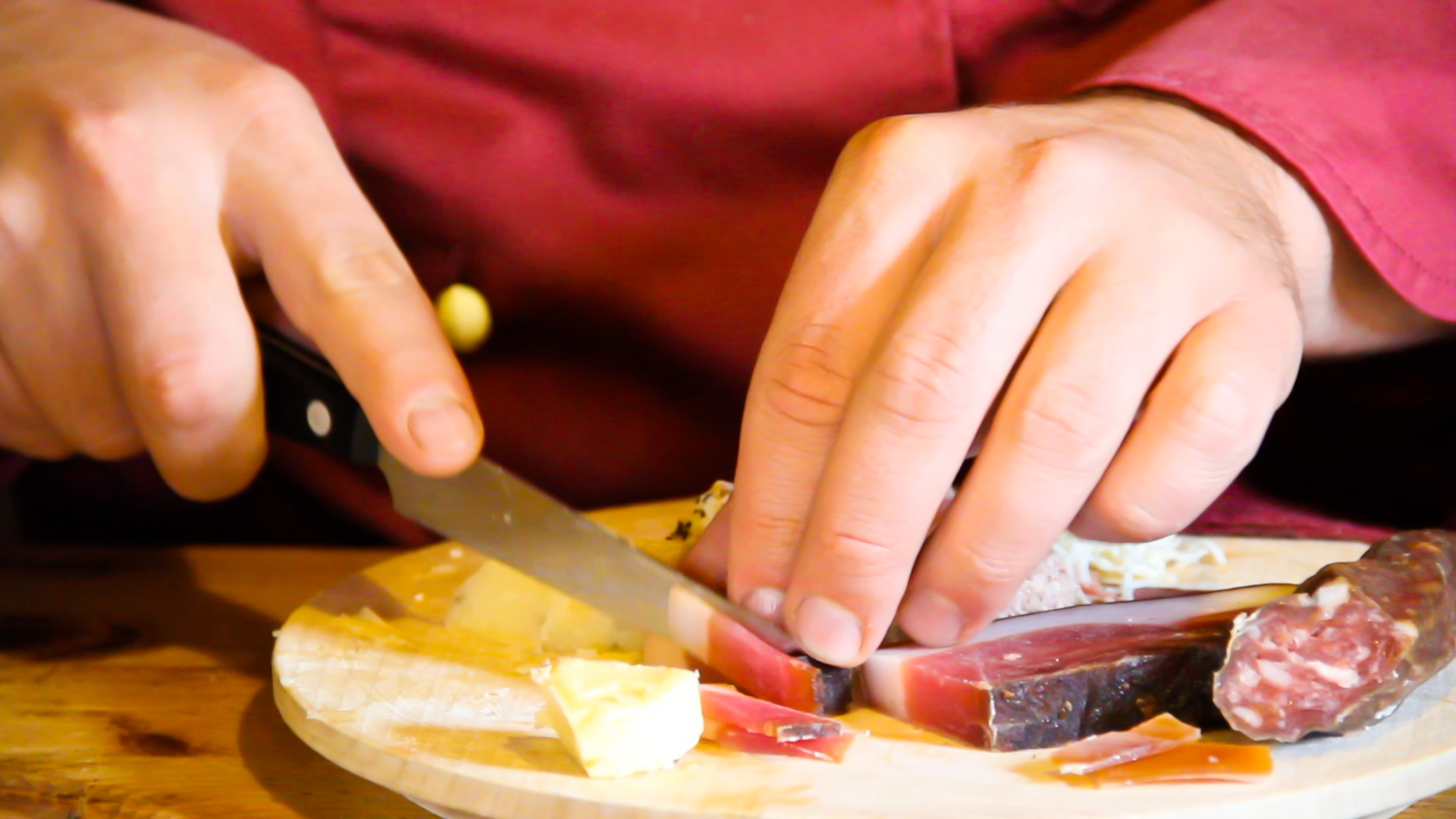 a person  up meat and cheese on a white plate