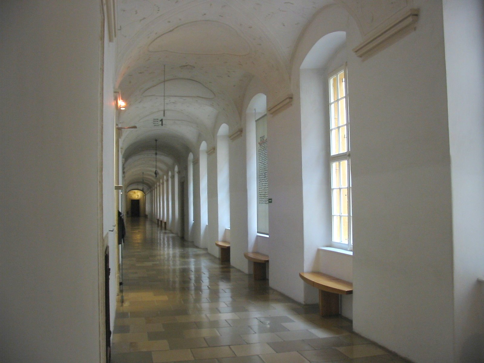 a long hallway with a bench next to two tall windows