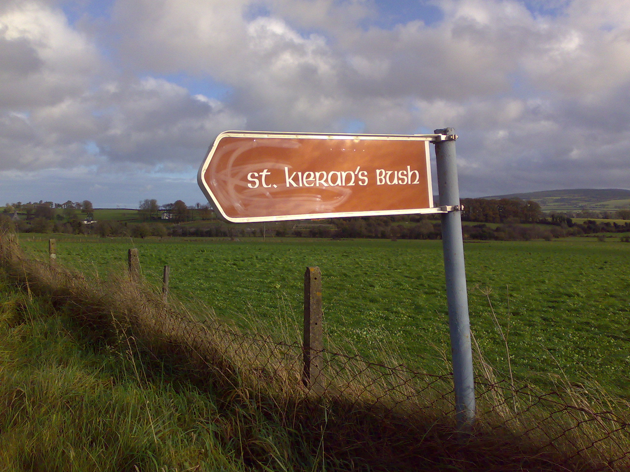 a wooden sign on a grassy field with a sky background