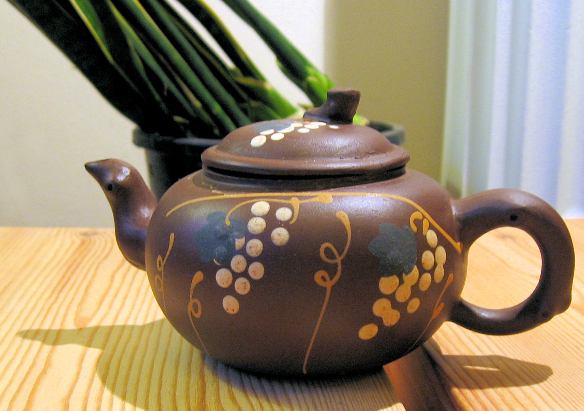 a tea pot sitting on a table in front of a potted plant