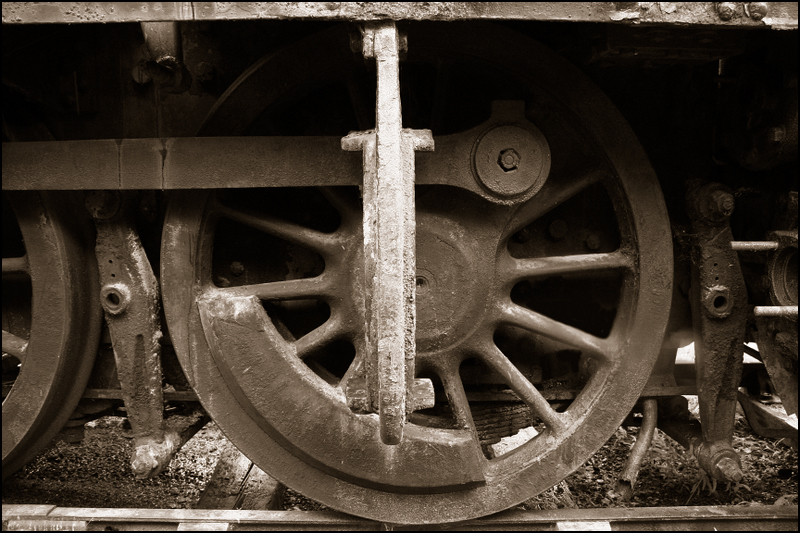 an old train wheel, in sepia tone, with a blurry background