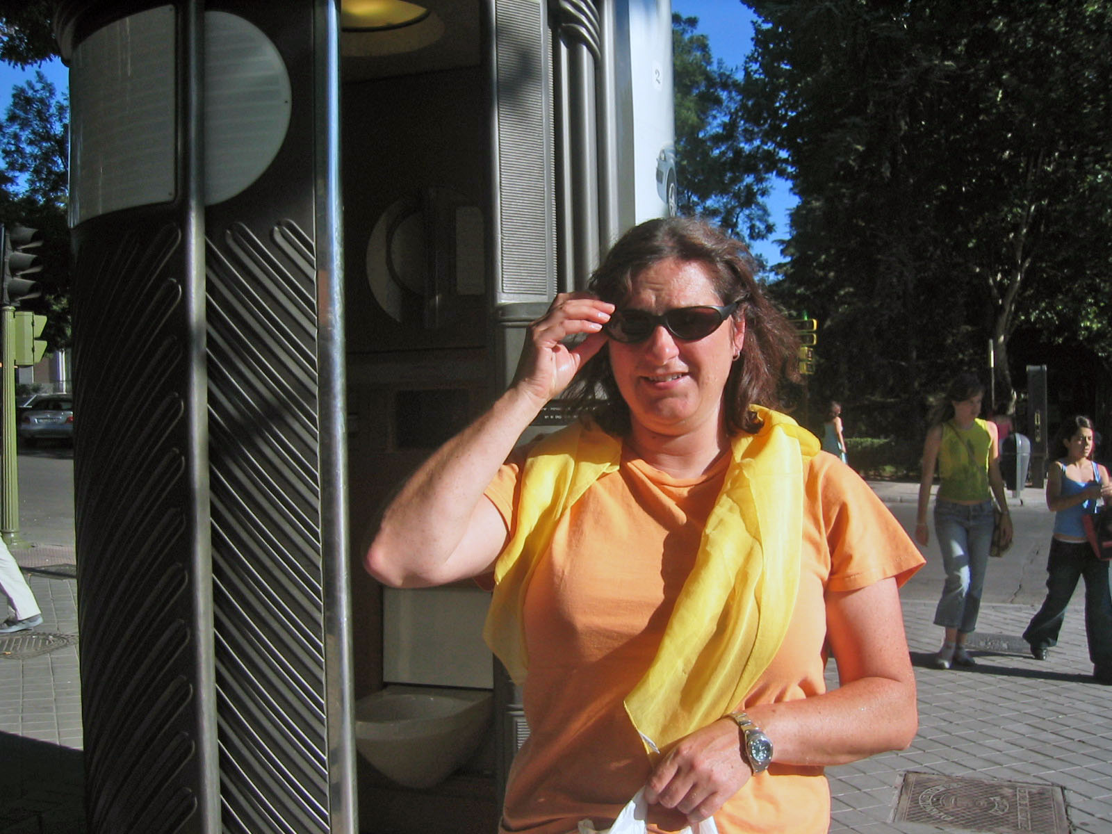 an older woman in sunglasses posing near an electronic speaker