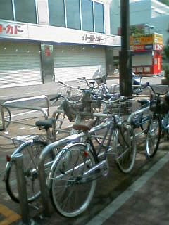 many bicycles parked on the sidewalk beside each other