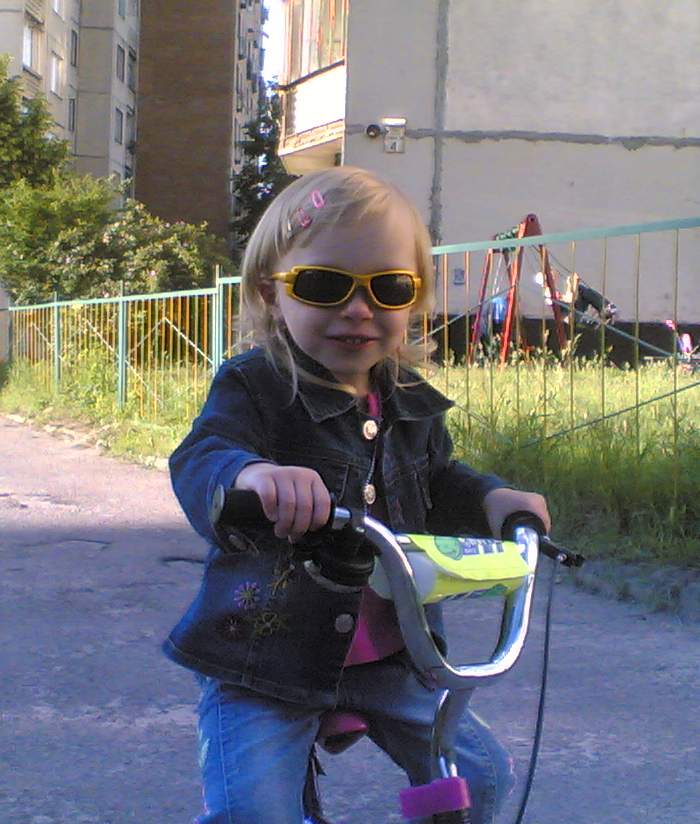 a girl wearing sunglasses on a little bike