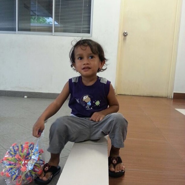 a young child is sitting on the wall near a bunch of toys